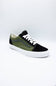 A low-top platform sneaker with an olive green and black suede upper, white laces, and a thick white platform sole, photographed on a light gray studio background.