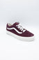A single Vans low-top sneaker in dark burgundy suede with white laces and a white rubber side stripe and sole, shown on a light gray studio background.