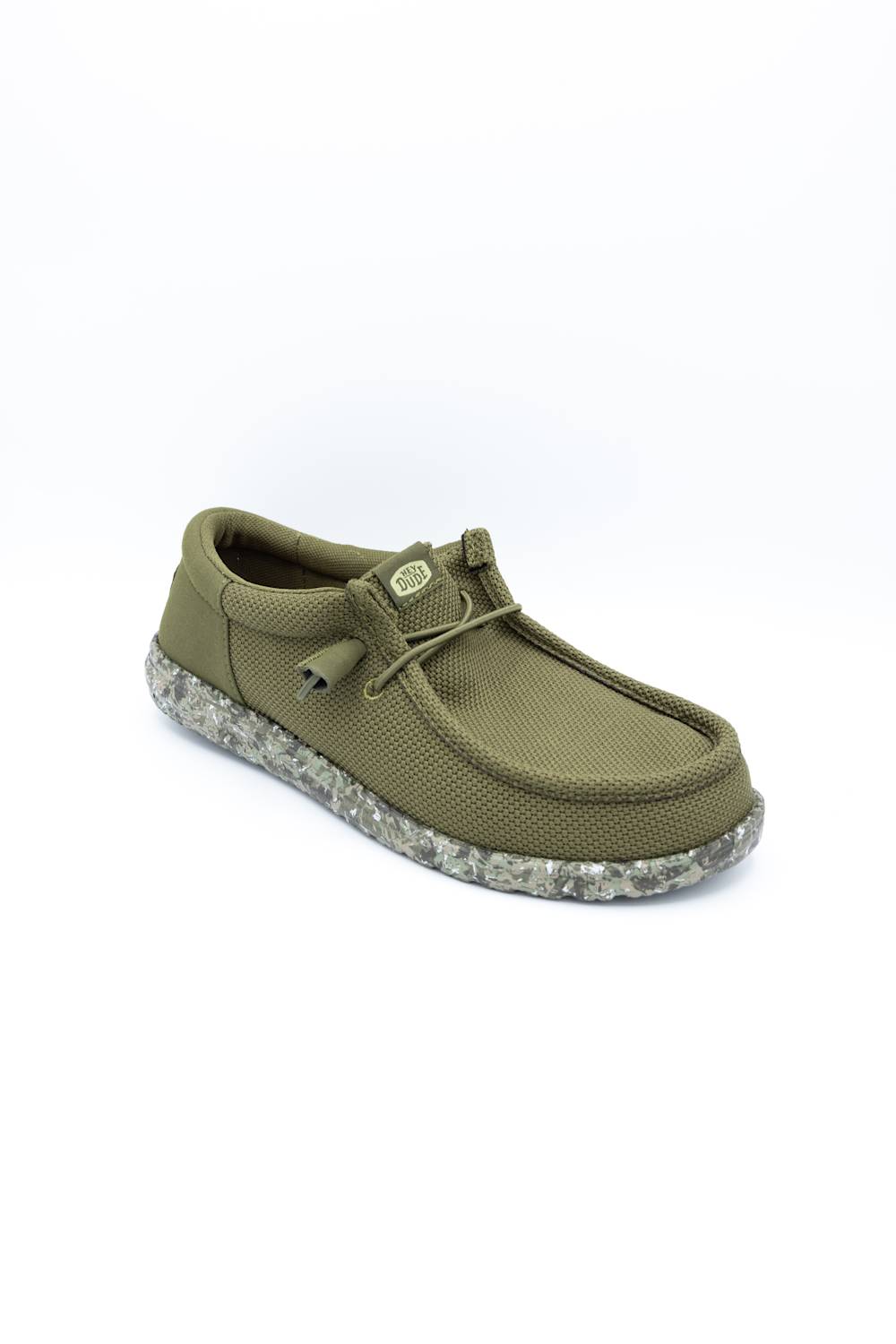 An olive green slip-on shoe with a textured fabric upper, matching laces, and a speckled gray and white sole, shown on a plain white background.