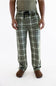A person wearing green and white plaid pajama pants with a dark drawstring, paired with a muted green shirt and brown slippers, shown against a plain white studio background.