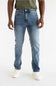 A person wearing light blue slim-fit jeans with a faded wash, paired with an olive green t-shirt and white sneakers, shown from the waist down against a plain white studio background.