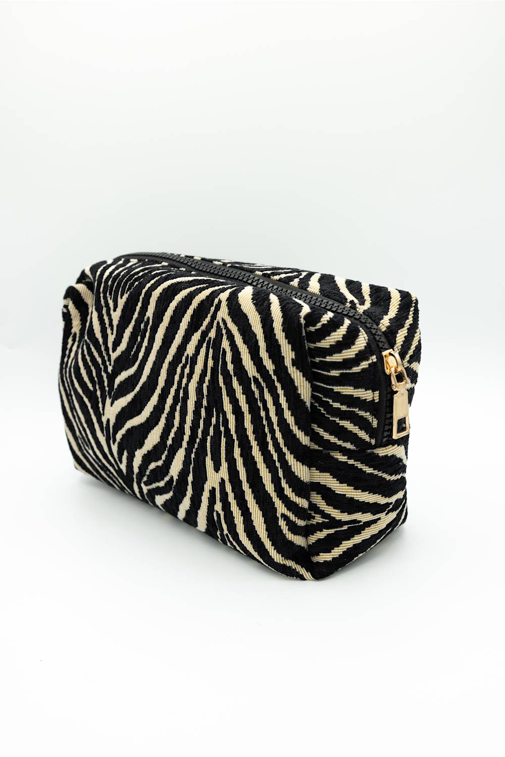 A zebra-print cosmetic pouch with a black and beige pattern and a gold zipper pull, photographed on a clean white background.