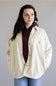 Person wearing a beige Carhartt jacket over a maroon hoodie on a plain background