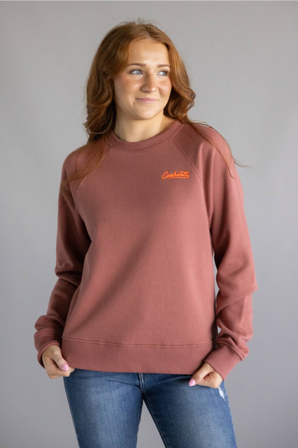 Dark red colored sweatshirt with orange Carhartt cursive letters on chest 