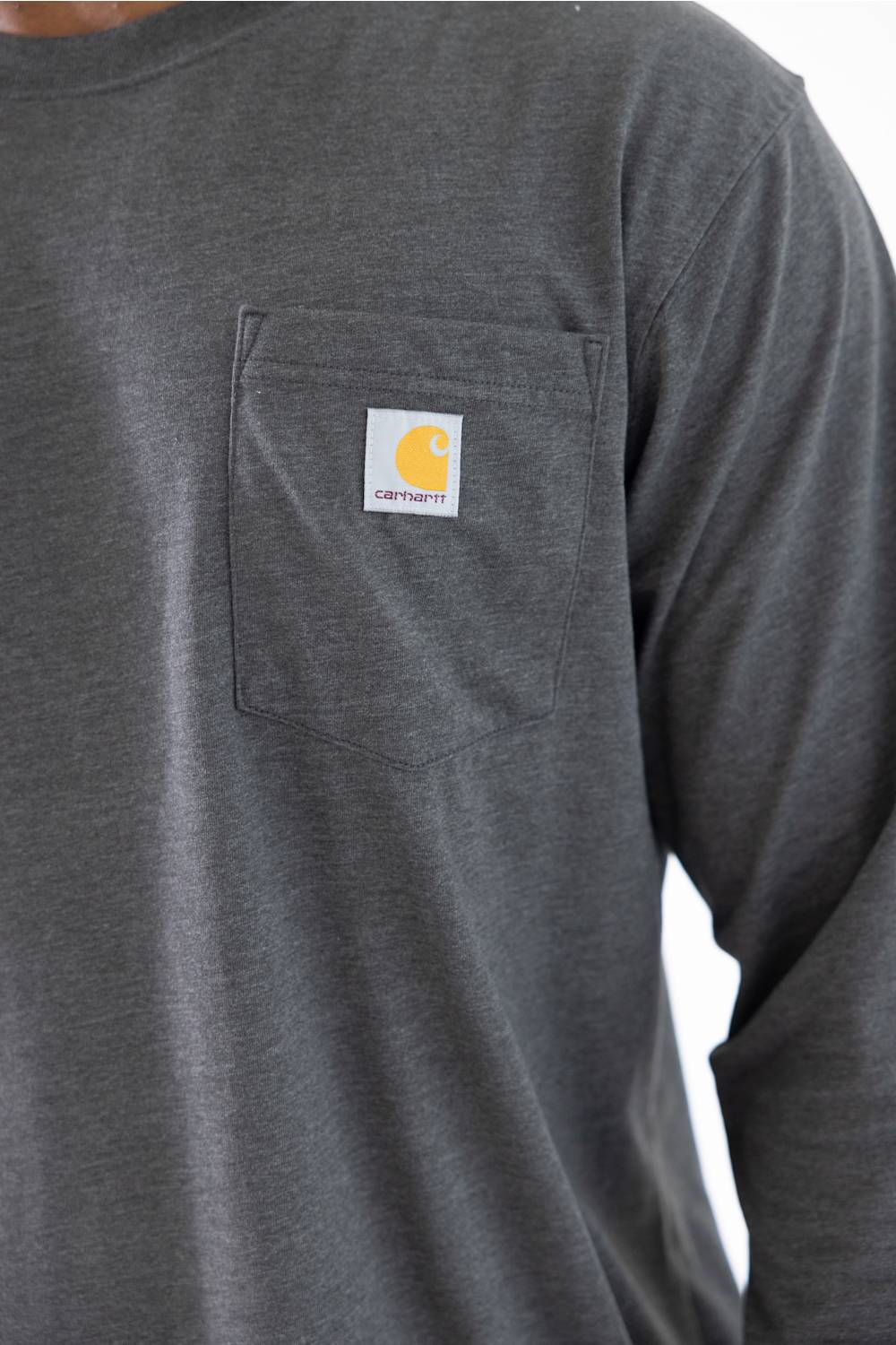 Close-up of a dark gray long-sleeve work shirt with a chest pocket featuring a Carhartt logo patch.