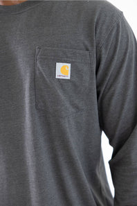 Close-up of a dark gray long-sleeve work shirt with a chest pocket featuring a Carhartt logo patch.