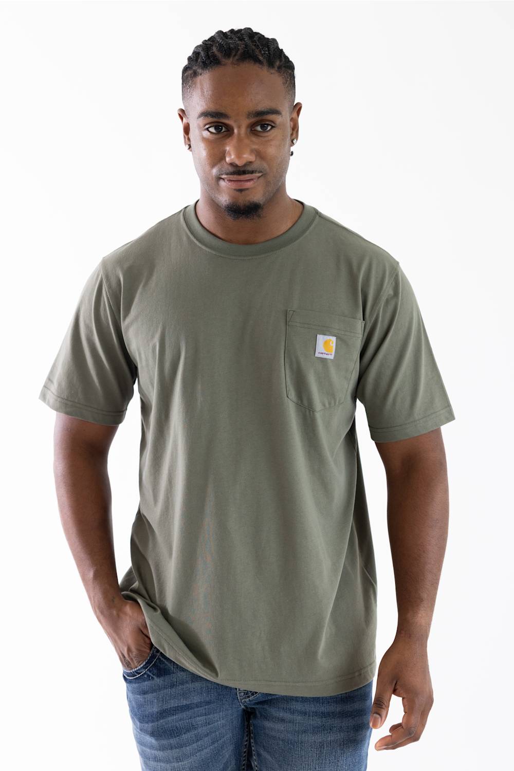 A man wearing a short-sleeve crewneck pocket t-shirt in olive green with a small Carhartt logo on the chest, paired with blue jeans, against a plain white background.