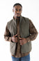 A man wearing a brown plaid button-down shirt with a olive green sleeveless vest layered over it, paired with blue jeans, against a plain white background.