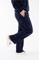 Side view of a woman wearing navy blue straight-leg fleece sweatpants featuring an all-over embroidered red and white candy cane pattern, with white sneakers and a matching sweatshirt.
