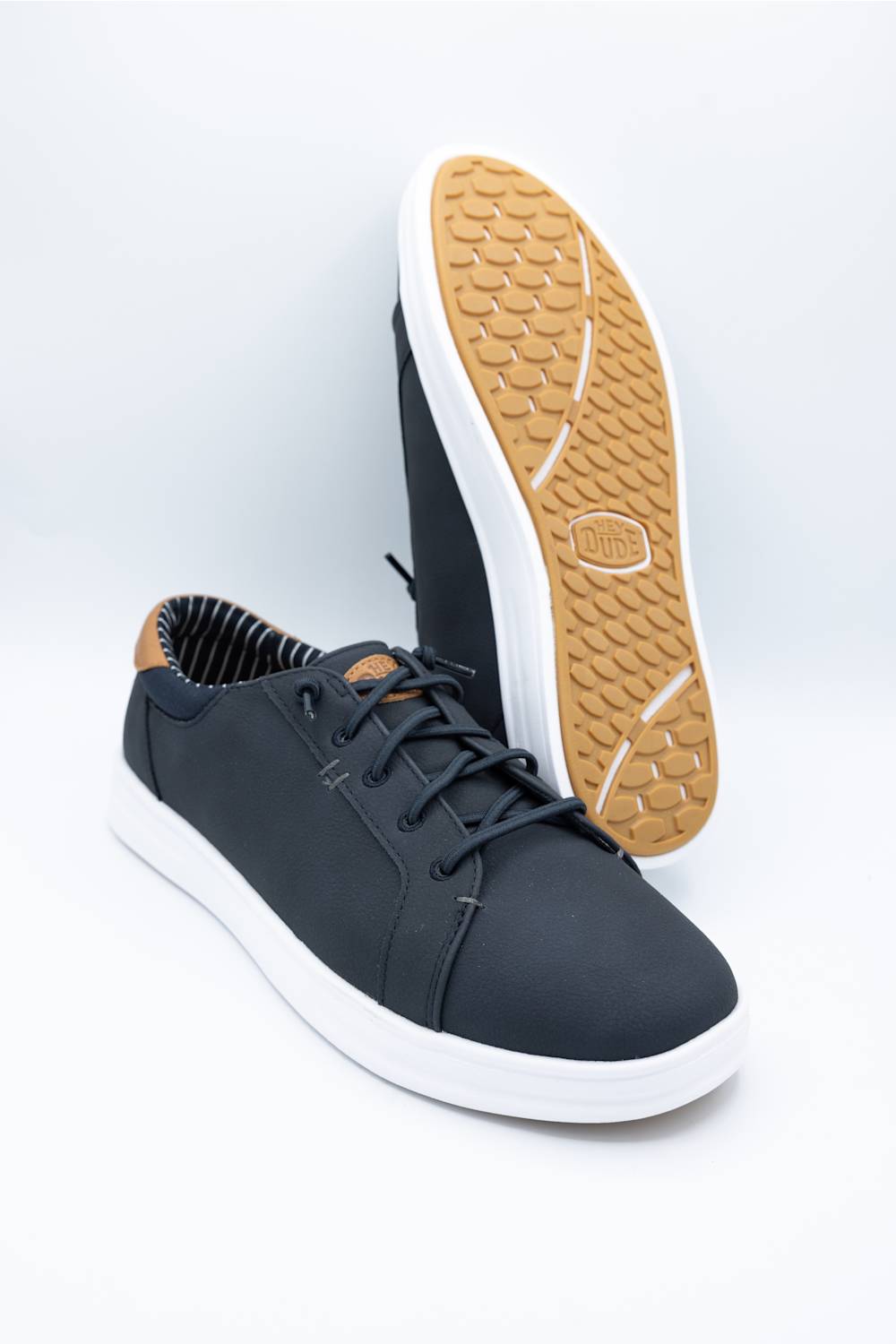 A single navy blue low-top sneaker shown from a top-down view on a white background. The shoe features a navy blue upper, matching navy laces, a tan/gum outsole, and a visible Vans 'Hey Dude' logo on the tan insole.