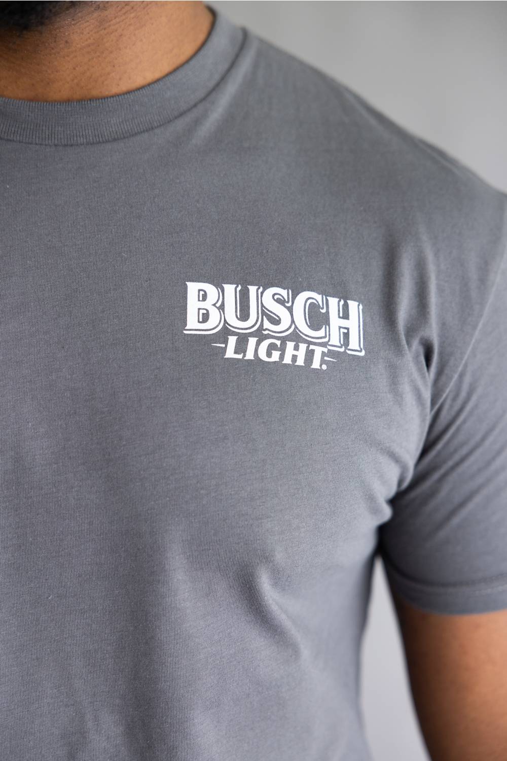 Close-up of a person wearing a heather gray crewneck t-shirt with a white 'BUSCH LIGHT' logo printed on the chest.