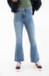 A person wearing light-wash blue flare jeans, a green top, a dark jacket, and burgundy sneakers, shown from the waist down against a plain white studio background.