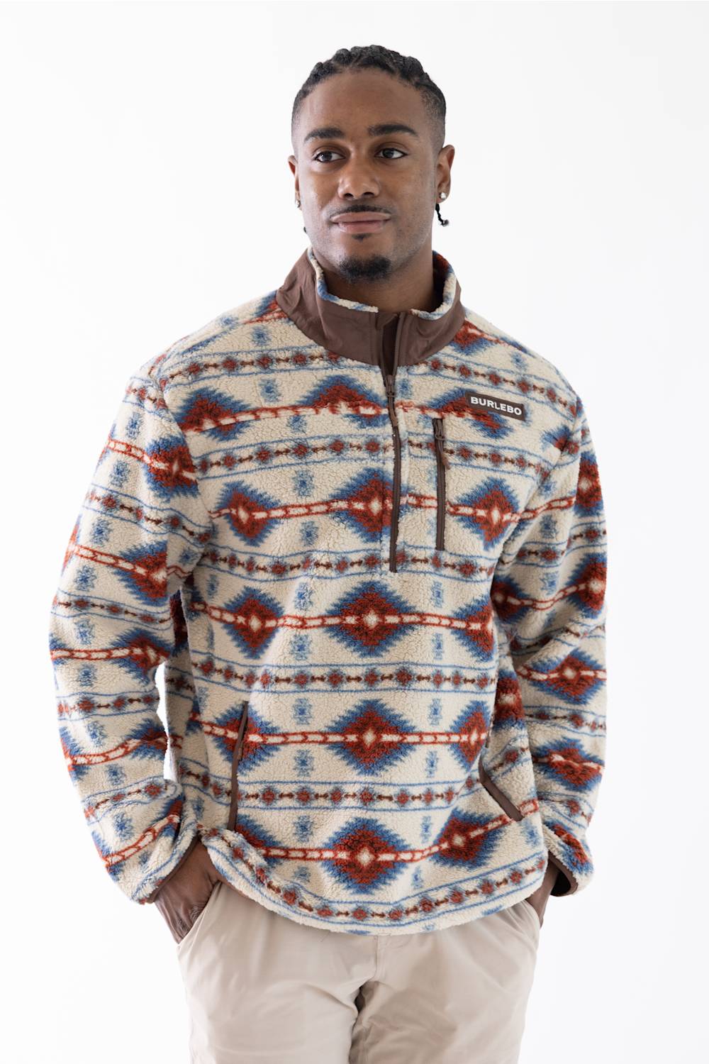 A man wearing a quarter-zip fleece pullover with a Southwestern geometric pattern in beige, blue, and rust red, paired with khaki pants, against a plain white background.