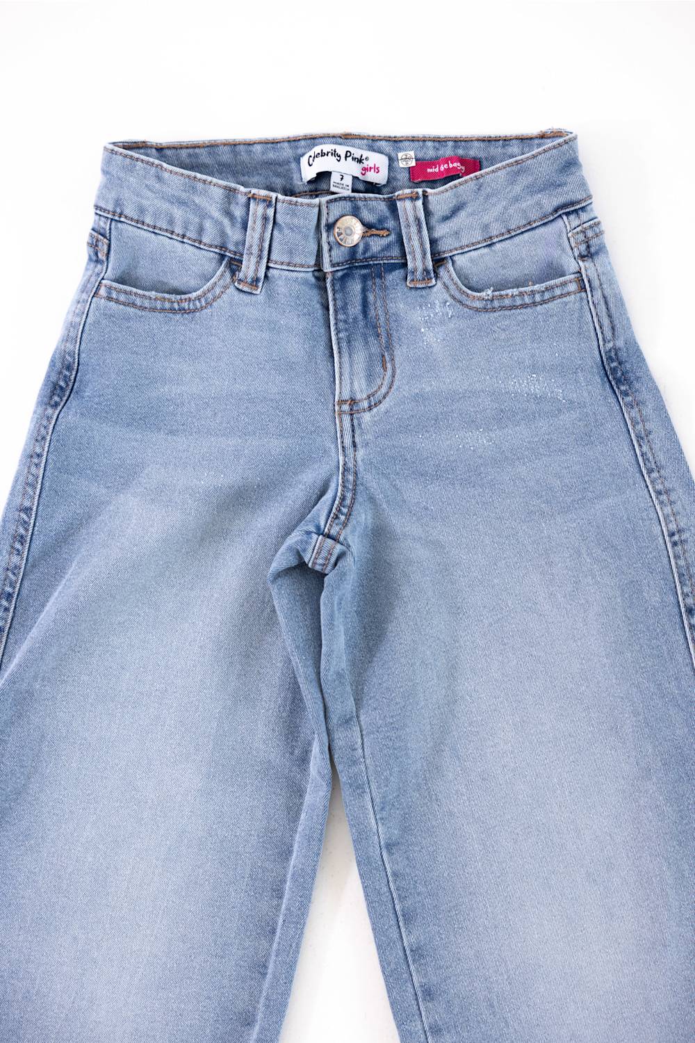 Light blue denim jeans laid flat on a white background, showing the front waistband, button closure, belt loops, and front pockets.