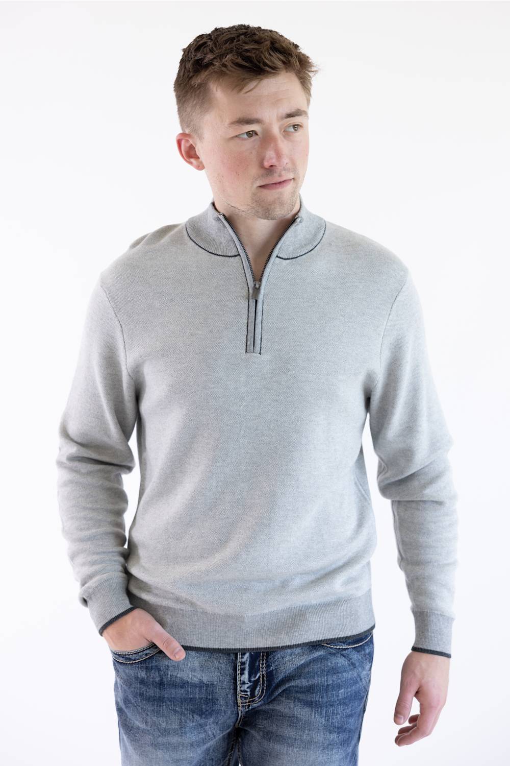 Model wearing an F/X Fusion platinum gray birdseye knit quarter-zip pullover sweater with ribbed cuffs and hem, paired with blue jeans.