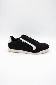 A black low-top sneaker with a white side stripe, black laces, and a white sole, photographed from the side against a plain white background.