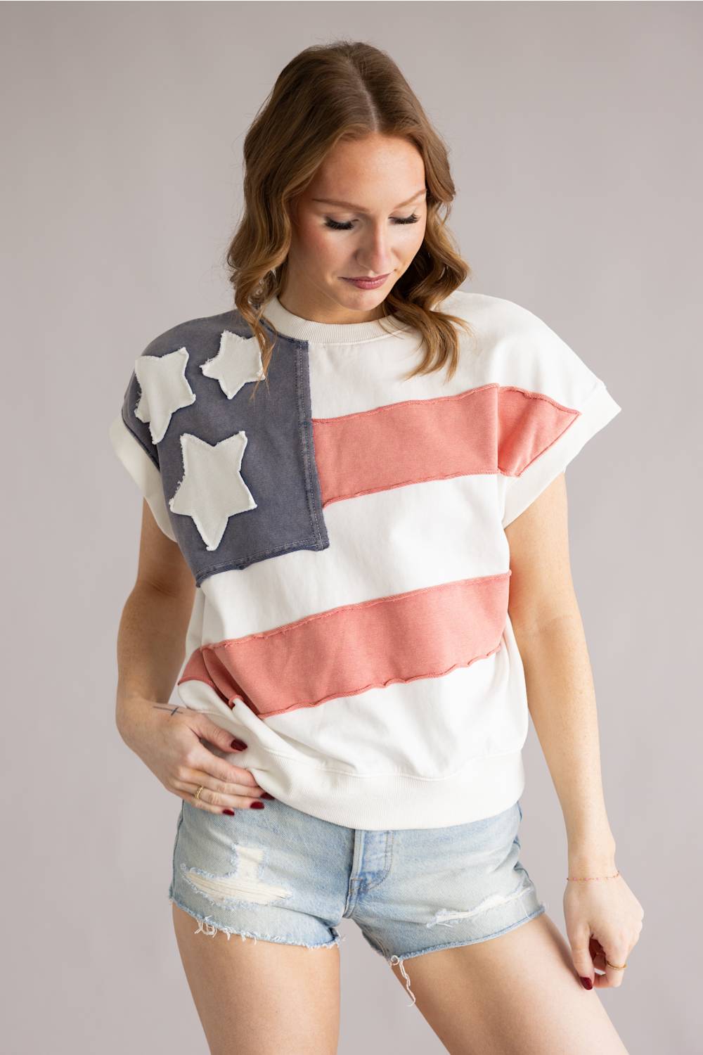 Woman wearing a t-shirt with an American flag design on a plain background