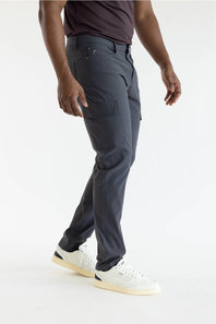 A person wearing dark charcoal gray cargo pants, a dark t-shirt, and white sneakers, shown from the waist down against a plain white studio background.