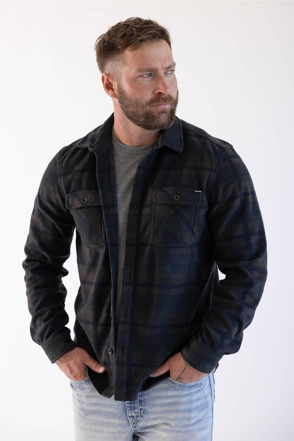 man wearing a plaid shacket with his hands tucked in his front pockets 