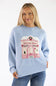 Blonde woman modeling a periwinkle blue christmas market storefront sweater with jeans