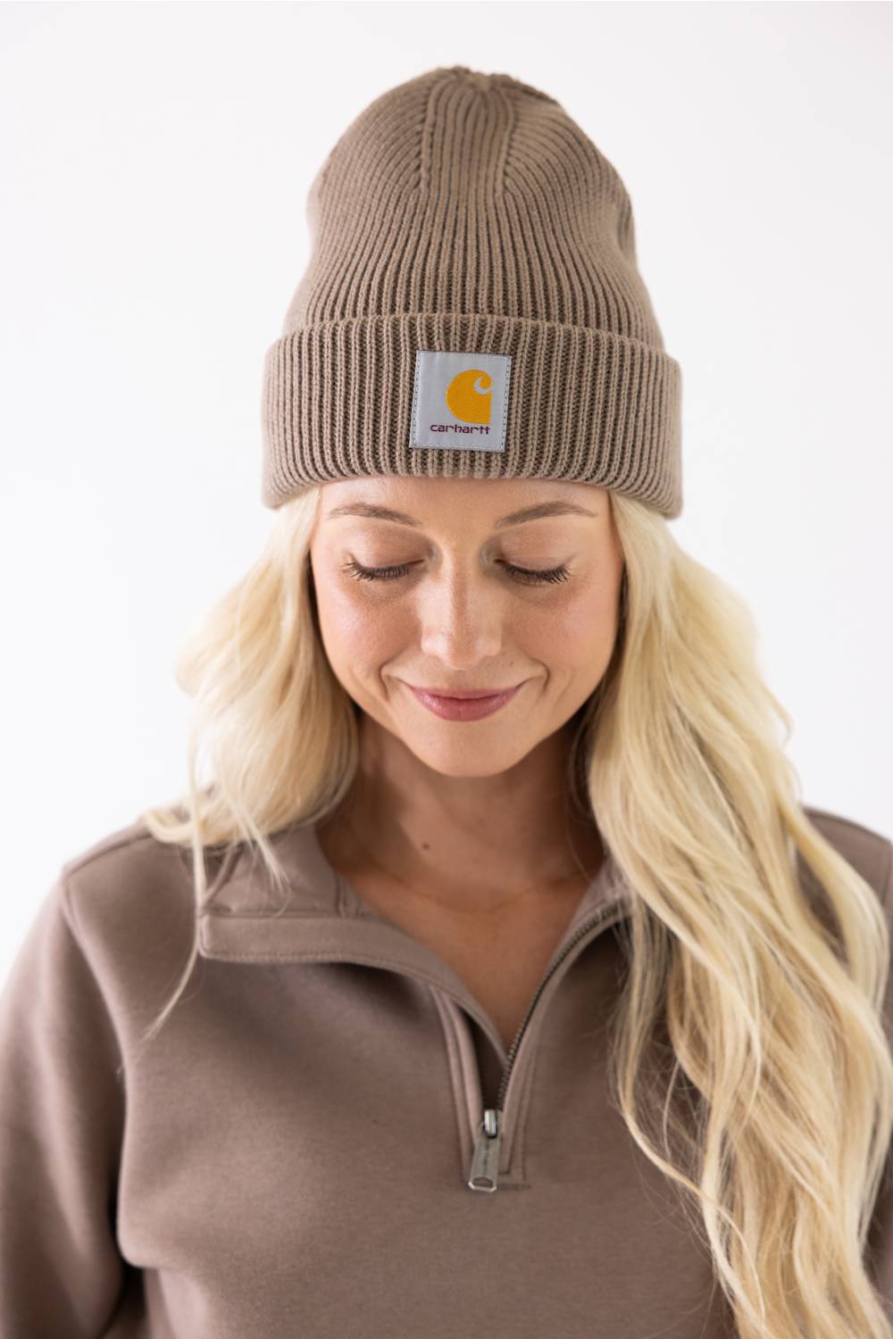 Blonde modeling a brown cuffed Carhartt beanie with carhartt logo on cuff 