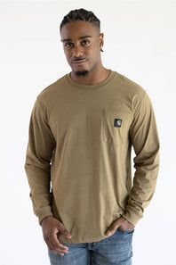 A man wearing a longsleeve light brown t-shirt with a black Carhartt patch on the upper left chest pocket.