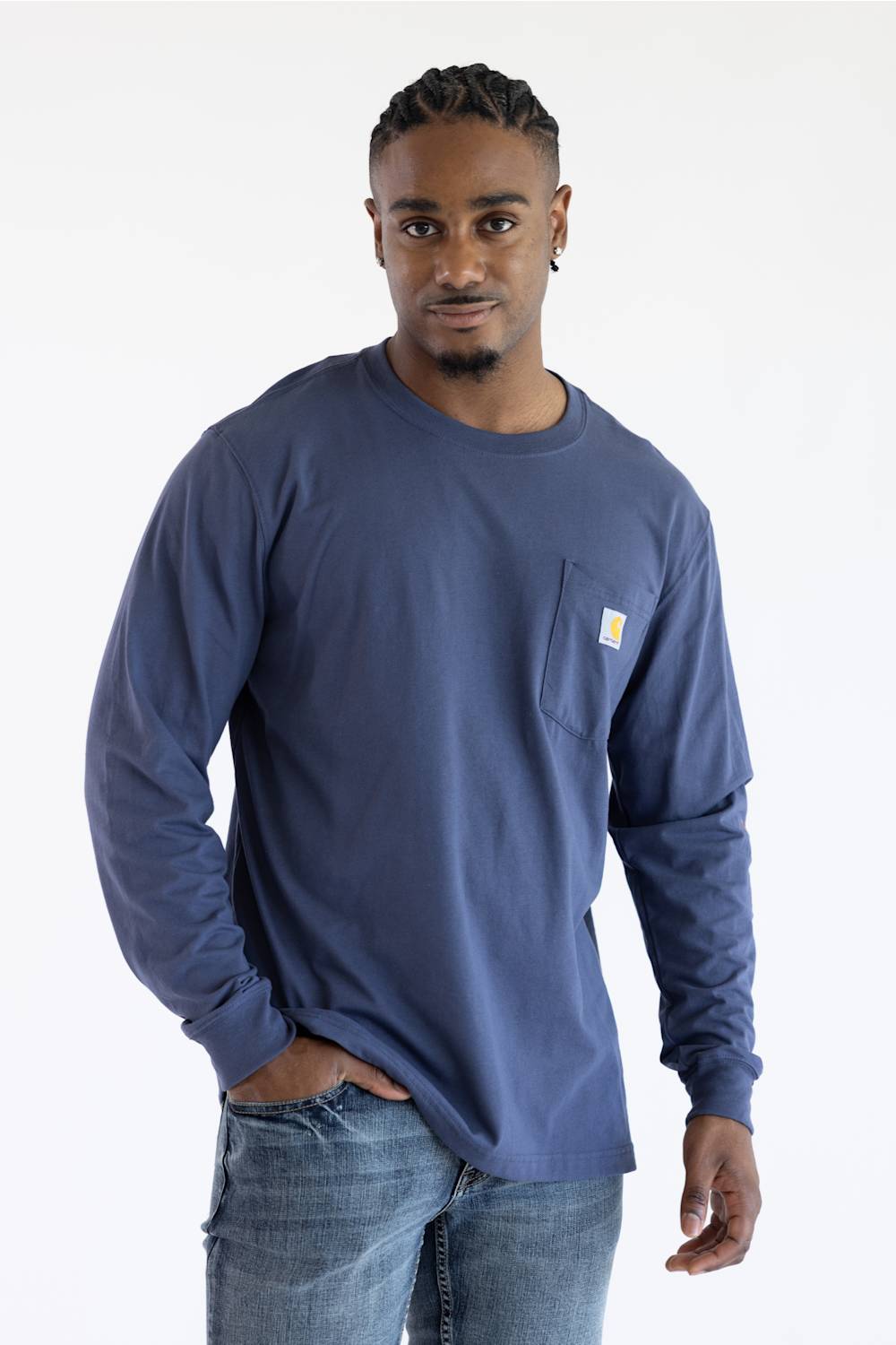 A man wearing a longsleeve Carhartt t-shirt in Superstorm blue with a classic Carhartt patch on the front chest pocket located on the upper left with a Carhartt logo down the left sleeve.