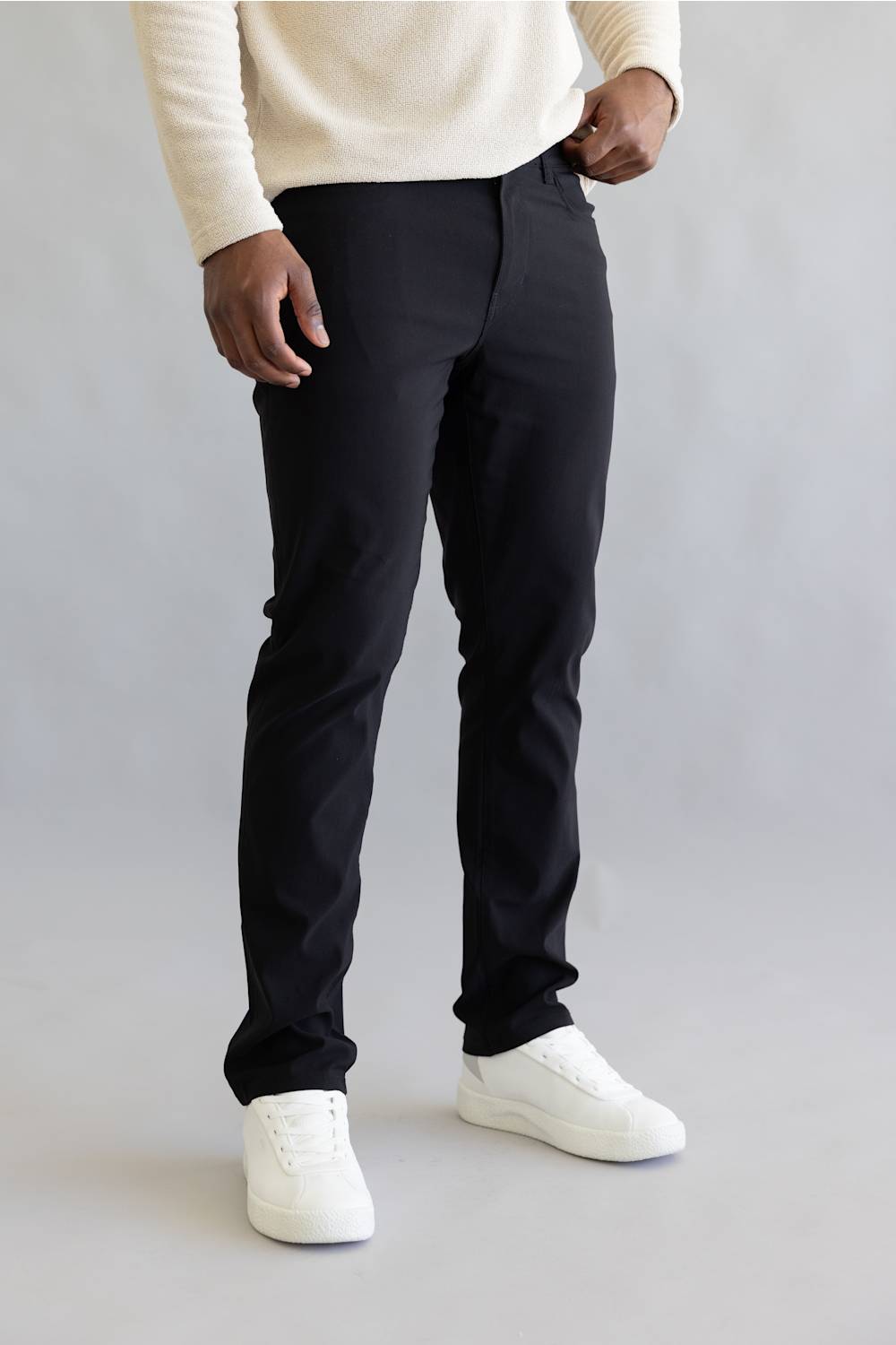 Man wearing black pants and white shoes on a plain background
