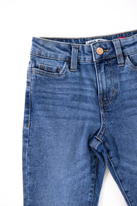 Close-up view of the waistband and front pockets of Celebrity Pink girls medium wash denim jeans, featuring a copper button, zip fly, belt loops, and subtle whiskering.