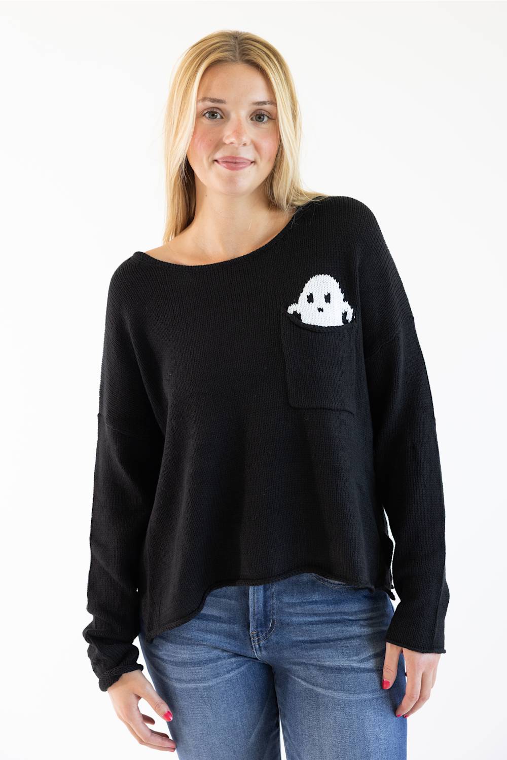 A woman wearing a black knit sweater with a white ghost graphic on the chest pocket, paired with blue jeans, against a plain white background.