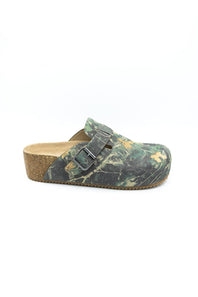 A single clog-style mule shoe with a green and brown camouflage pattern upper, a cork wedge heel, and a double-buckle strap closure, shown against a plain white background.