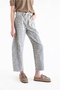 A model wearing cropped wide-leg jeans with a gray and white leopard print, styled with a brown t-shirt and brown suede mule loafers against a plain white background.