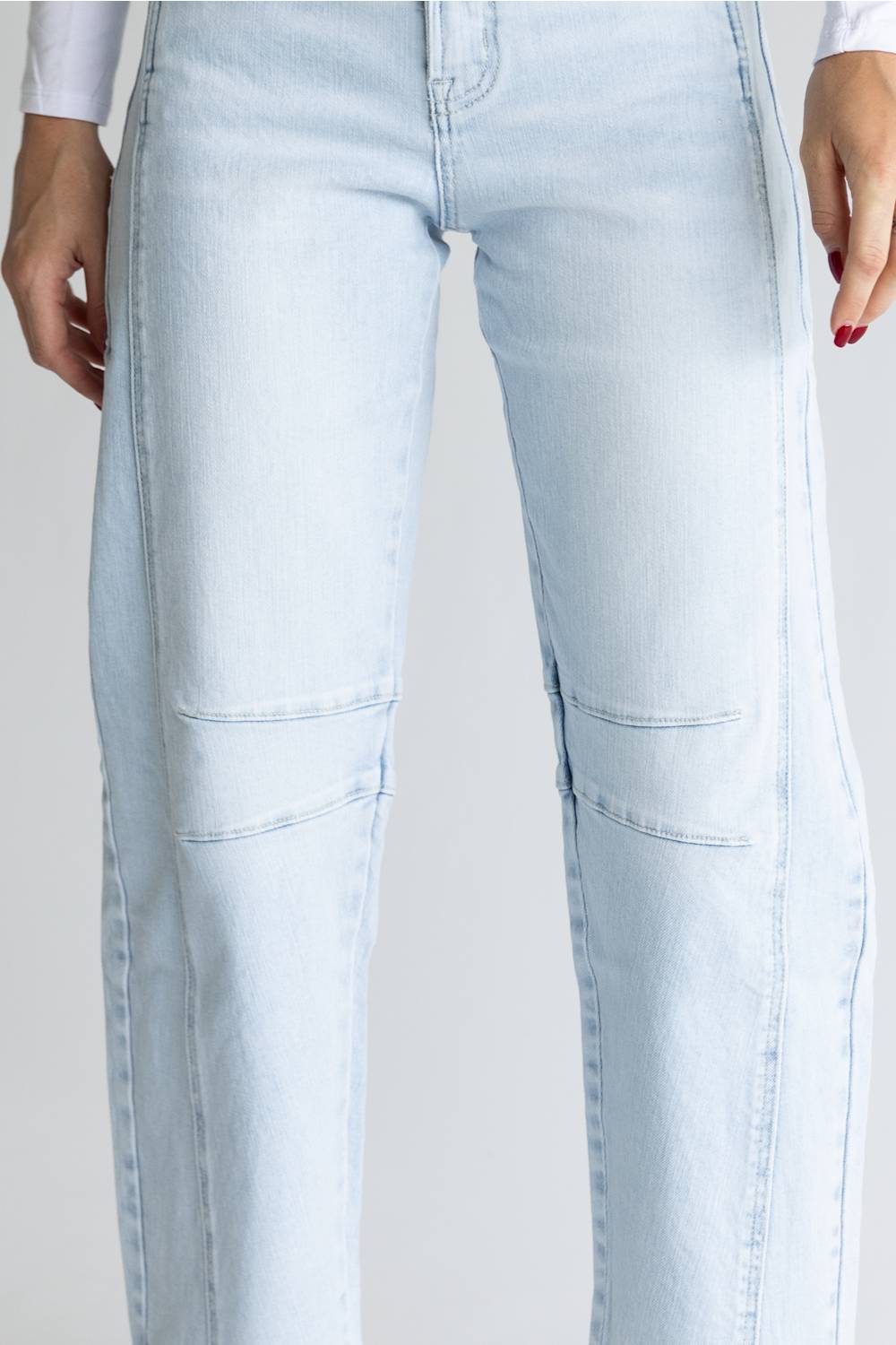 Light wash blue denim jeans with unique diagonal seam details running down the front of the thighs, shown on a model against a light gray background.
