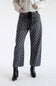 A model posed from the waist down wearing black barrel-leg jeans featuring a white polka dot pattern, black drawstring eyelet waistband, and dual front pockets, styled with black leather heeled boots on a plain white background.