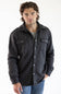 A man wearing a dark charcoal gray button-up flannel shirt jacket with two chest pockets and silver snap buttons, paired with blue jeans.