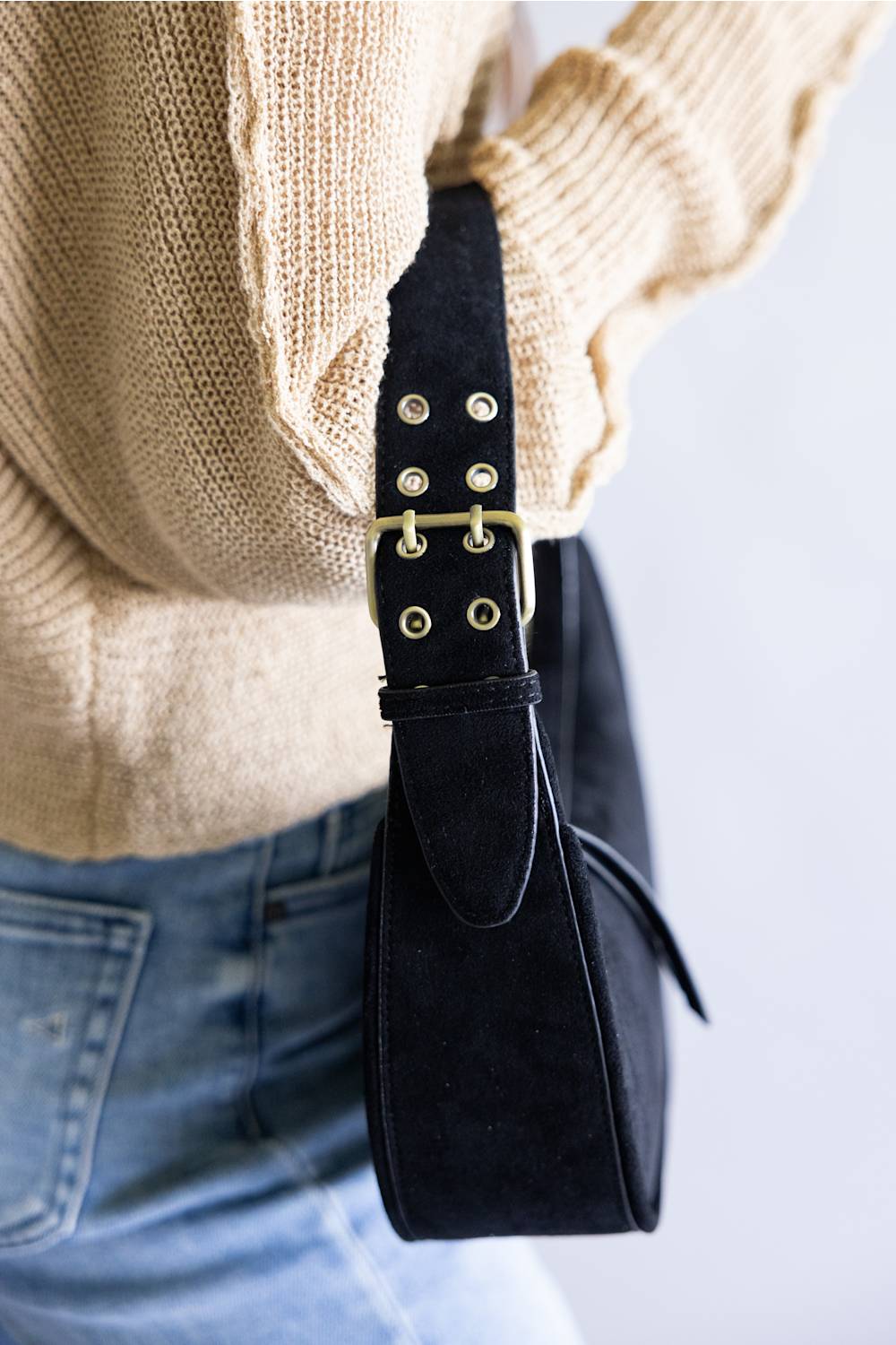 Crescent shaped faux suede shoulder bag with an adjustable buckle detail on strap