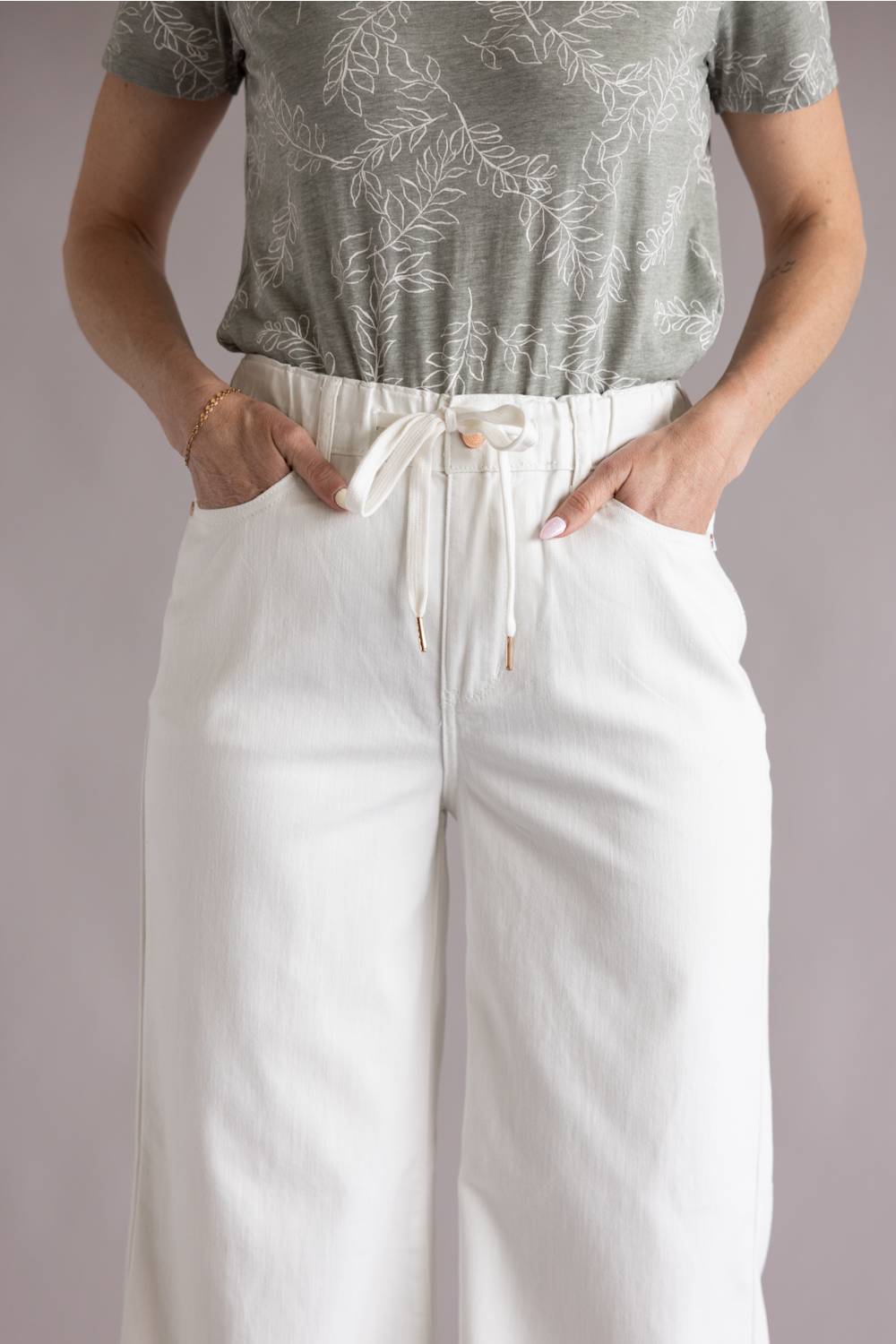 Judy Blue White Featherweight Palazzo Jeans for Women in White; Person wearing a green patterned top and white pants with a drawstring on a plain background