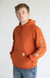 Man wearing a burnt orange colored hoodie, with Carhartt logo down the left arm sleeve. 