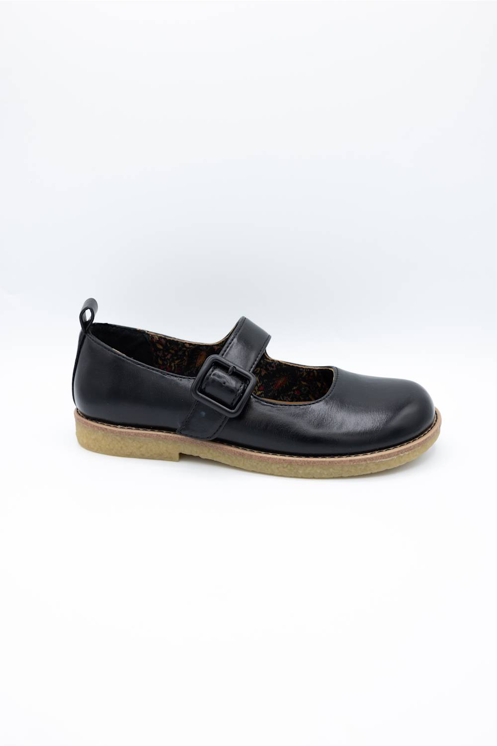A single black leather Mary Jane shoe with a hook-and-loop strap and a tan sole, photographed on a white background.
