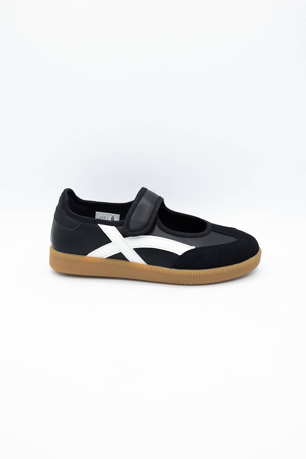 A black slip-on sneaker with a white side stripe and a brown gum sole, shown from the side against a plain white background.