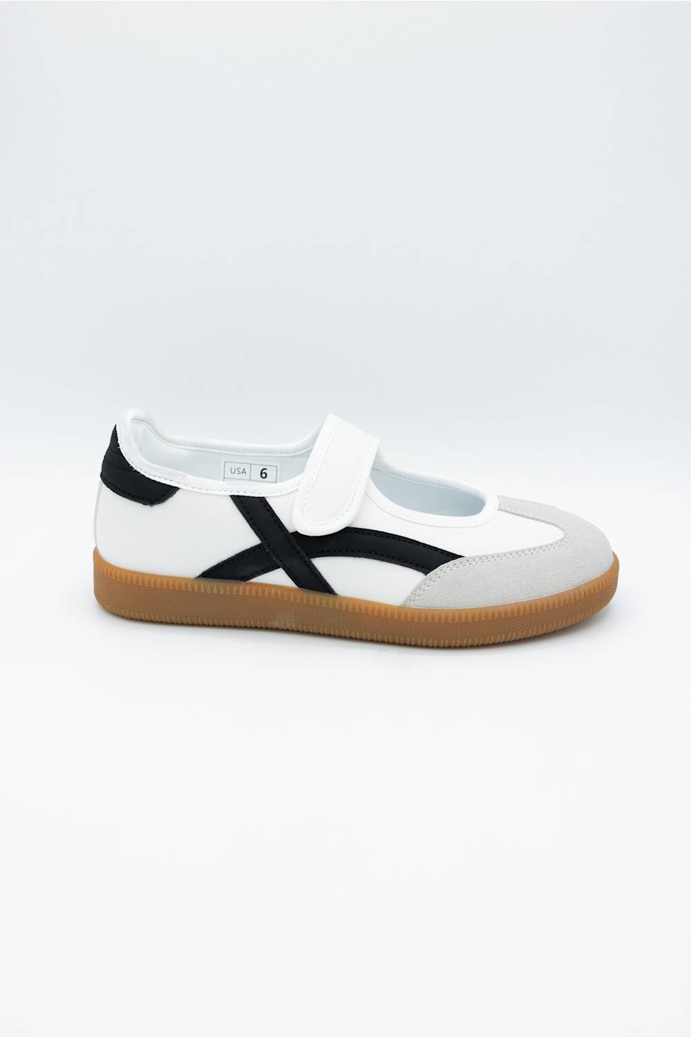 A white low-top casual shoe with a black side stripe, a white hook-and-loop strap across the top, and a brown gum sole, shown against a plain light gray background.