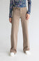 A model is wearing a pair of wide-leg beige jeans with a matching belt, styled with a floral long-sleeve shirt and white sneakers against a plain light gray background.
