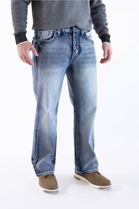 Front view of a male model wearing True Luck Mac Loose Straight medium-wash jeans with light fading and whiskering, a grey long-sleeve sweater, and brown casual shoes against a plain white background.