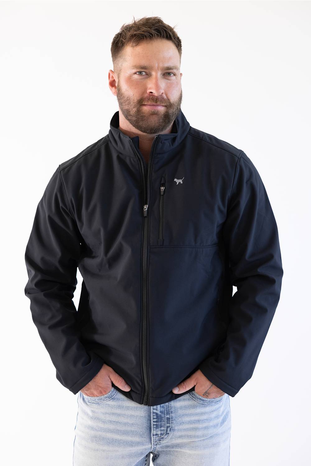 A man wearing a dark navy blue zip-up jacket with a small white horse logo on the left chest, paired with light blue jeans, against a plain white background.