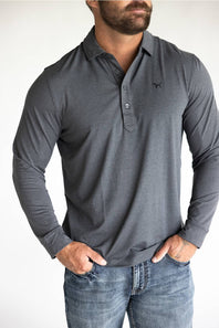 A man wearing a dark gray long-sleeve polo shirt with a small embroidered logo on the left chest, paired with blue jeans, against a plain white background.