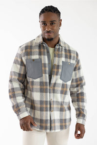 A man wearing a long-sleeve plaid button-up shirt with gray chest pockets, photographed against a plain white studio background.