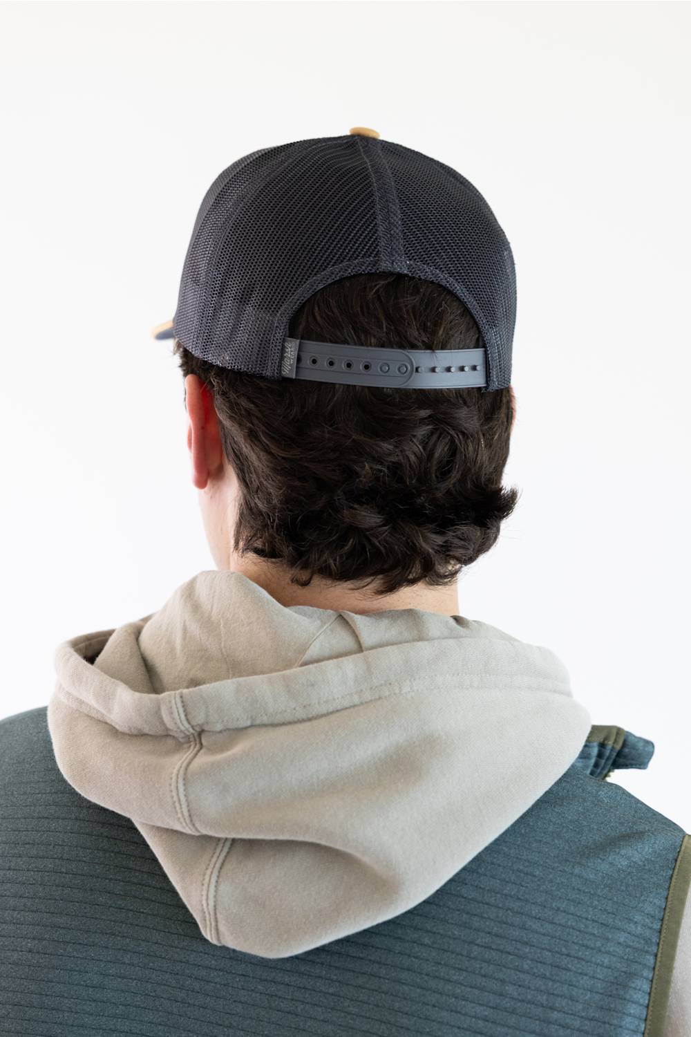 A picture from the back of a man wearing a navy blue snapback hat.