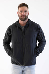 man standing in front of a white background looking off to the side in a patagonia jacket 
