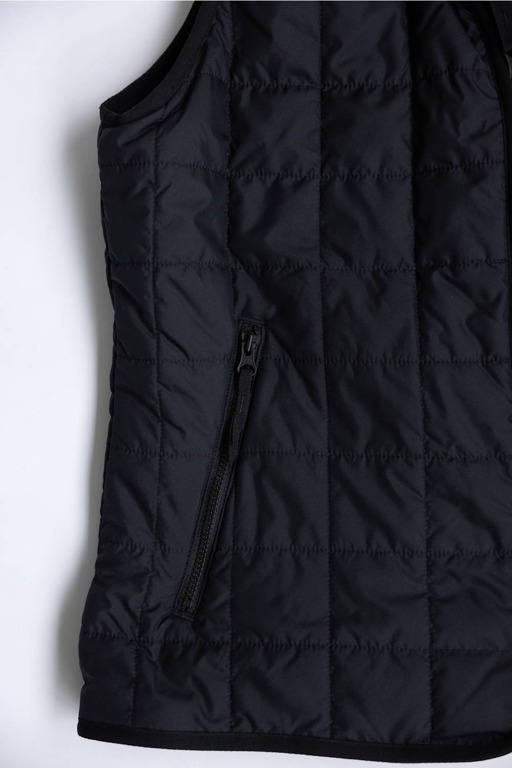 Close-up of a black quilted puffer vest with horizontal stitching and a vertical zippered pocket on a white background.