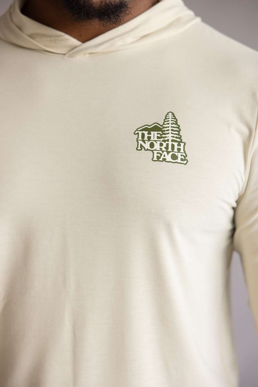 Close-up of green The North Face logo on The North Face Adventure Keep Climbing Hoodie in Desert Taupe